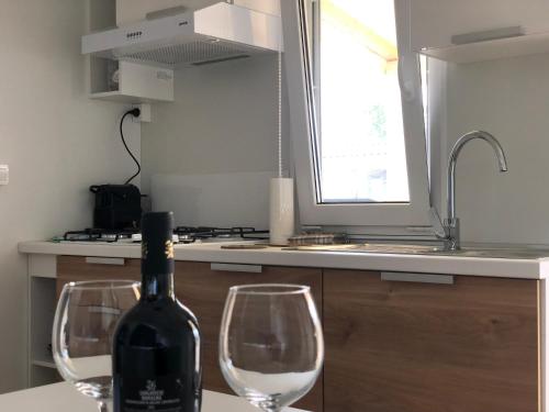 a bottle of wine sitting on a counter with two wine glasses at Tiny house on the beach in Lido di Classe