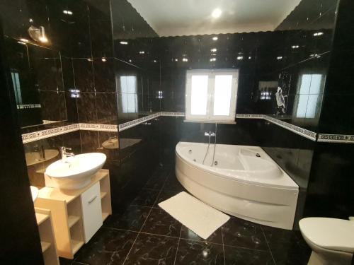 a black bathroom with a tub and a sink at Casa das Marinhas in Caminha