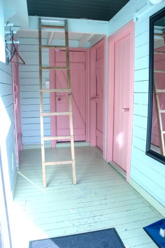 a ladder in a room with a pink door at Kræmmervika Rorbuer - Rustic Cabins & Hostel in Lofoten in Ballstad