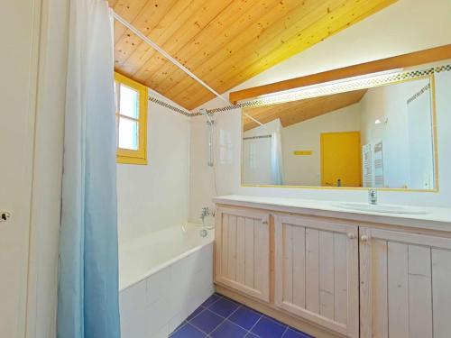 un bagno con vasca, lavandino e specchio di Charmante maison avec accès direct plage, jardin clos, 6 couchages, et ménage inclus - Noirmoutier - FR-1-224B-75 a Noirmoutier-en-l'lle
