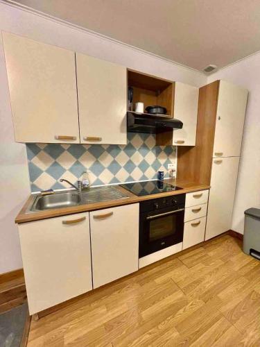 une cuisine avec des armoires blanches et un évier dans l'établissement Joli T2 plein cœur de Wazemmes - Lille, à Lille