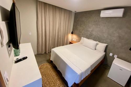 a hotel room with a bed and a television at Pousada Baobá in Jericoacoara