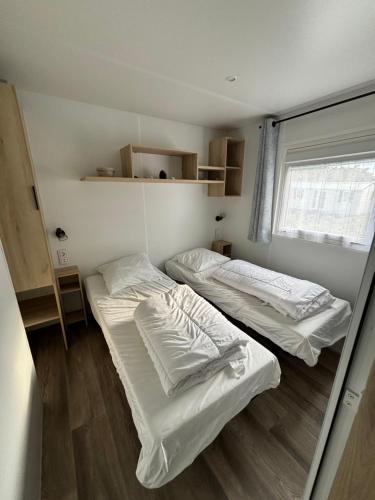 two beds in a small room with a window at Camping Quiberon - Mobilhomes Bord de Mer, Conguel in Quiberon