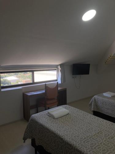 a bedroom with two beds and a desk and a window at HAUSHostel in Vinhedo