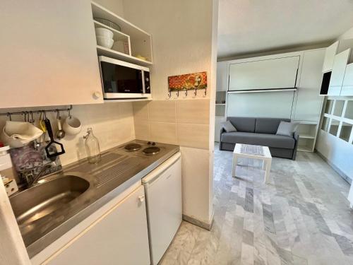 une petite cuisine avec un évier et un canapé dans l'établissement Studio climatisé avec grande terrasse et parking privé, proche plage et commerces - FR-1-716-60, à La Grande Motte