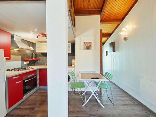 une cuisine avec des armoires rouges et une table et des chaises dans l'établissement Maison de Vacances avec Piscine Chauffée, Proche Mer à Brétignolles-sur-Mer - FR-1-224A-69, à Bretignolles-sur-Mer