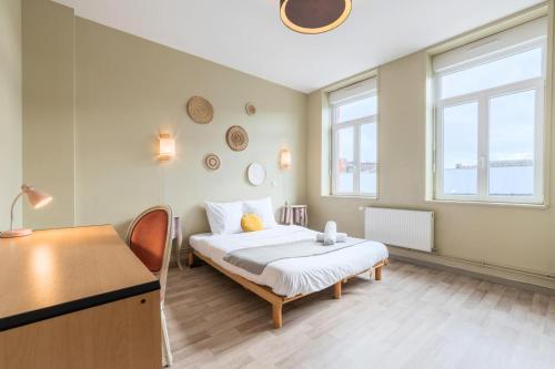 une chambre avec un lit, un bureau et des fenêtres dans l'établissement Grande maison 5 chambres charmante et confort à Roubaix - Idéal pour visite de la métropole, à Roubaix