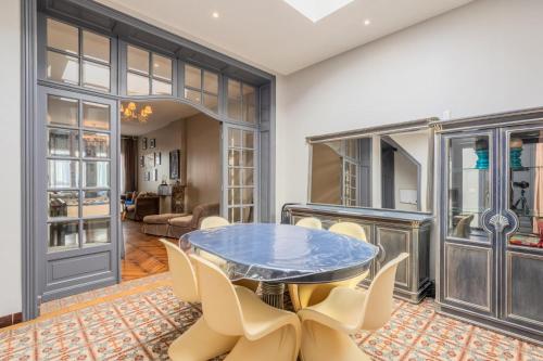 une salle à manger avec une table et des chaises en verre dans l'établissement Grande maison 5 chambres charmante et confort à Roubaix - Idéal pour visite de la métropole, à Roubaix