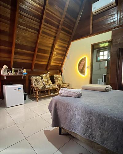a bedroom with a bed and chairs in a room at Chalé da Chapada in Chapada dos Guimarães