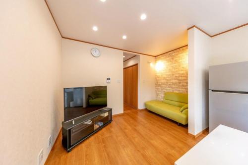 Una sala de estar con un sofá verde y un televisor. en ソレイユ白浜, en Shirahama