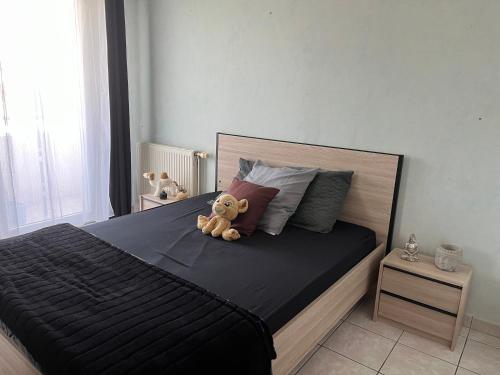 un ours en peluche assis sur un lit dans l'établissement chambre équipée vue sur jardin, à La Celle-sous-Gouzon