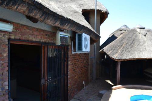 un edificio de ladrillo con techo de paja y puerta en abuntu guest house, en Vanderbijlpark