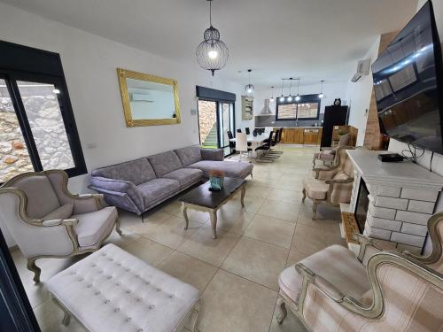 a living room with a couch and chairs and a table at שקד באופק - וילה מקסימה עם 2 בריכות וג'קוזי מול החרמון in Metulla