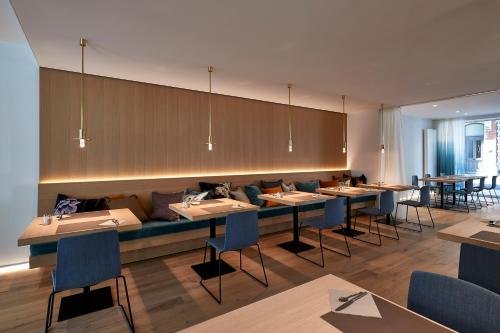 a restaurant with tables and chairs and a long couch at Parkhotel Roeselare in Roeselare