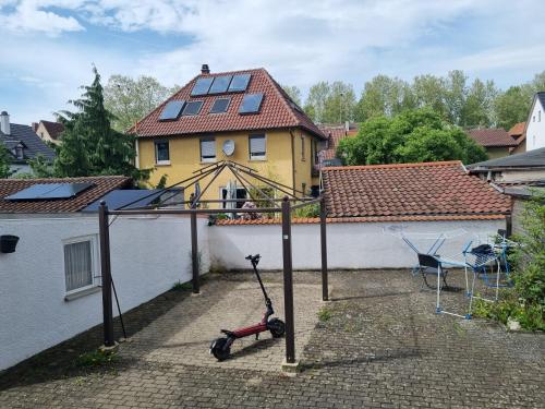 a scooter parked in a courtyard in front of a house at Charmantes helles Zimmer zentrumnah und naturnah in Göppingen