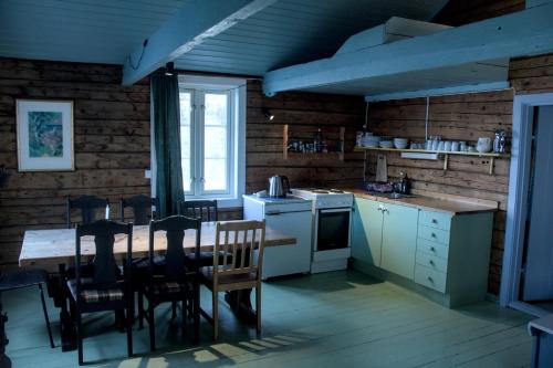 a kitchen with a table and chairs in a room at Kræmmervika Rorbuer - Rustic Cabins & Hostel in Lofoten in Ballstad