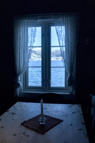a candle sitting on a table in front of a window at Kræmmervika Rorbuer - Rustic Cabins & Hostel in Lofoten in Ballstad