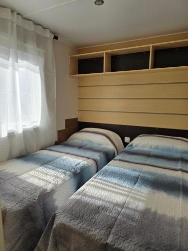 two beds in a room with a window at camping Pradon in Arnuero