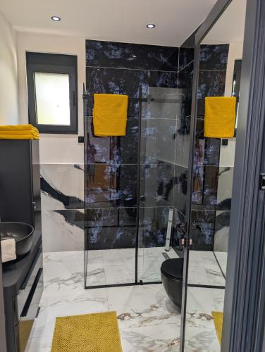 a bathroom with a glass shower with yellow towels at Apartmani Sunce Anja in Dobra Voda
