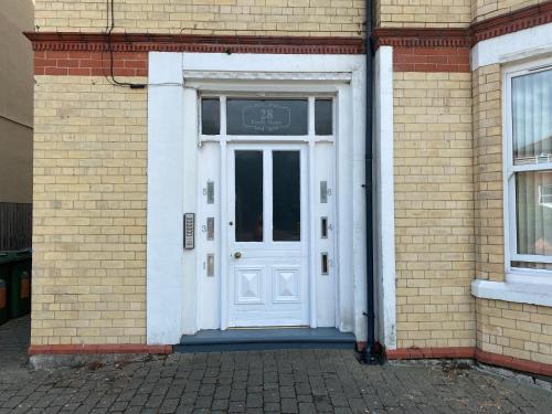 a white door on the side of a brick building at Pendle House - Apt 4 - 3 min walk to beach & Shops! in Colwyn Bay