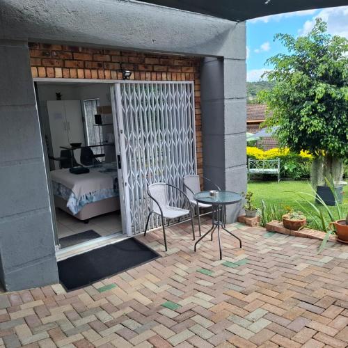 a patio with a table and a bed and a bedroom at Sleep Haven Self-Catering Accommodation - Nelspruit in Nelspruit