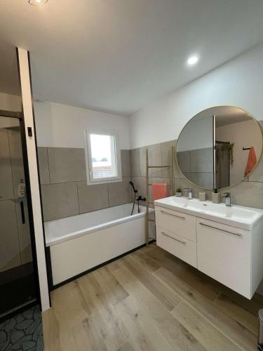 une salle de bain avec une baignoire, un lavabo et un miroir dans l'établissement Jolie maison à 800 m de la mer, à Hillion