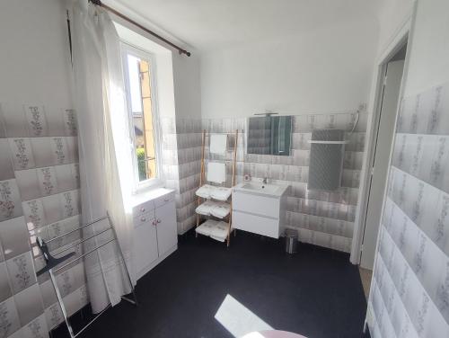 une salle de bain blanche avec un lavabo et un miroir dans l'établissement Chez Nadette, à Saint-Vincent-de-Cosse