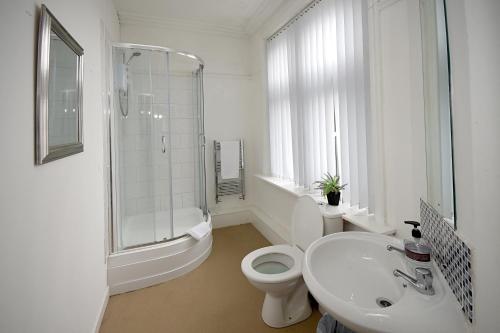 a white bathroom with a toilet and a sink at Sheridans Budget Accomodation in Wallasey