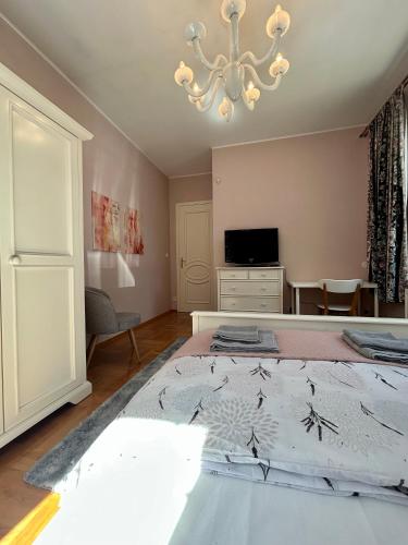 a bedroom with a large bed and a chandelier at Villa Otolice obok Łowicza, 6 sypialni, basen, sauna, snooker, 50 minut od Warszawy i Łodzi in Łowicz