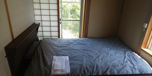 a small bedroom with a blue bed with a window at Yamanouchi sekisan chi in Yokokura