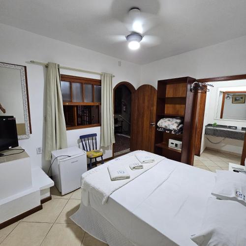 a bedroom with a large white bed and a television at GH Bizkaia in Florianópolis