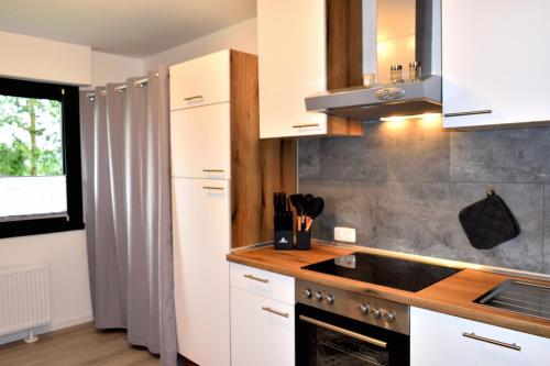 a kitchen with white cabinets and a sink at Ferienwohnung Soonwaldblick in Schwarzerden