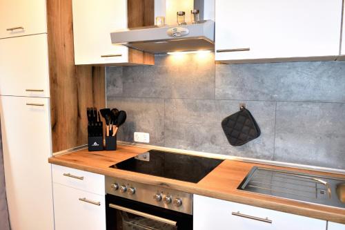 a kitchen with white cabinets and a stove top oven at Ferienwohnung Soonwaldblick in Schwarzerden
