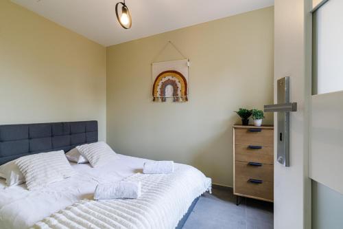 Cette chambre comprend un lit avec des draps blancs et une commode. dans l'établissement Évasion Côtière, à Villeneuve-Loubet