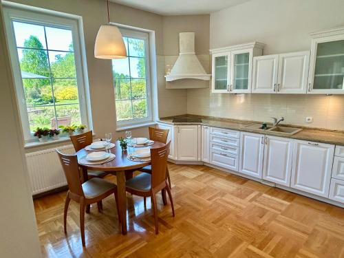 a kitchen with a table and chairs and windows at Villa Otolice obok Łowicza, 6 sypialni, basen, sauna, snooker, 50 minut od Warszawy i Łodzi in Łowicz