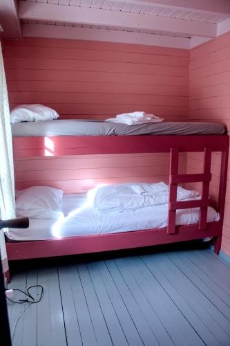 two bunk beds in a room with red walls at Kræmmervika Rorbuer - Rustic Cabins & Hostel in Lofoten in Ballstad