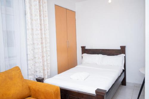 a small bedroom with a bed and a chair at Serene Getaway Studio Along Ngong road-Nairobi,Kenya in Nairobi