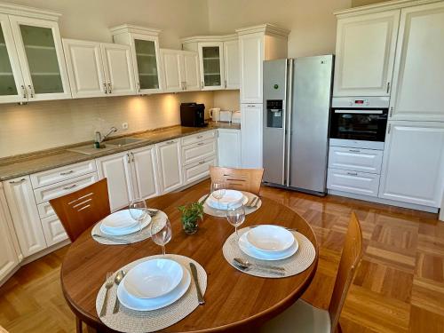 a kitchen with a wooden table with plates and wine glasses at Villa Otolice obok Łowicza, 6 sypialni, basen, sauna, snooker, 50 minut od Warszawy i Łodzi in Łowicz