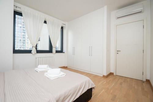 a white bedroom with a bed with two towels on it at BW Vista in Belgrade