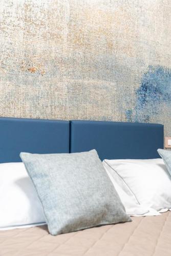 a bed with two pillows in front of a wall at Hotel Baia di Talamone in Talamone