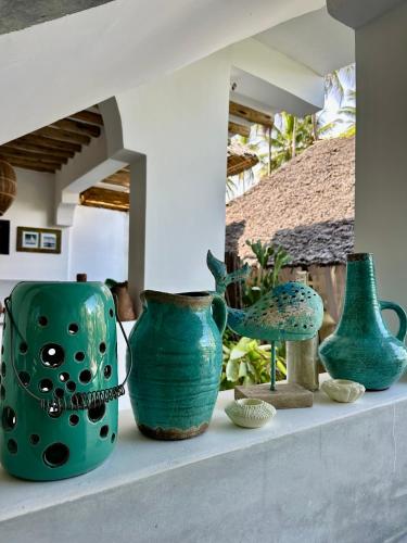 a group of green vases sitting on a shelf at Olamanga Beach Villa Adults Only in Jambiani