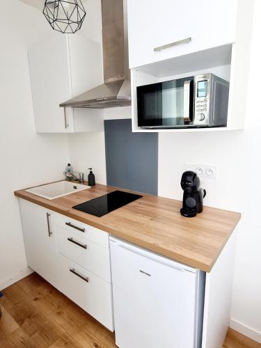 eine Küche mit weißen Schränken und einer Mikrowelle in der Unterkunft Studio 1 Cozy en centre-ville - Puy duFou in Les Herbiers