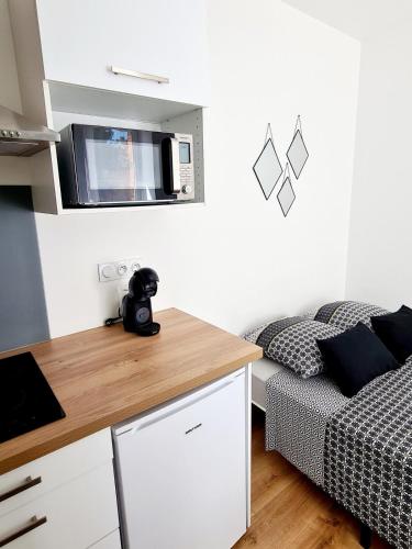 - une petite cuisine avec un lit et un four micro-ondes dans l'établissement Studio 1 Cozy en centre-ville - Puy duFou, aux Herbiers