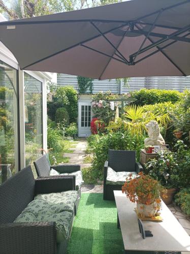 un patio avec des chaises et une table avec un parasol dans l'établissement Chambre d'hôtes, à Brive-la-Gaillarde