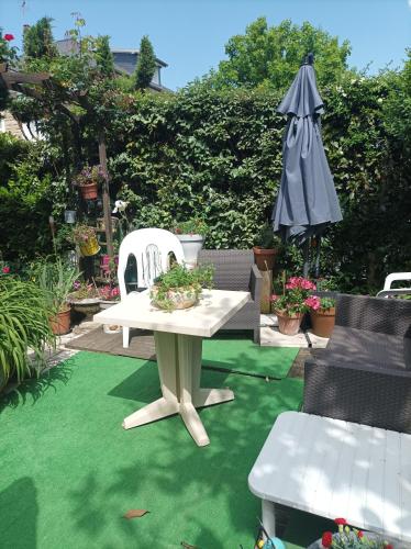 un patio avec une table, des chaises et un parasol dans l'établissement Chambre d'hôtes, à Brive-la-Gaillarde