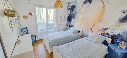 une chambre avec deux lits et un tableau au mur dans l'établissement CoeurDeSable - Appartement T3 Hyper Centre Arcachon - Parking, à Arcachon