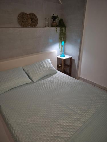 1 dormitorio con 1 cama con colcha blanca y lámpara en Quarto 1 na Glória, en Río de Janeiro