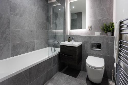 a bathroom with a toilet and a sink and a tub at Modern 2 Bedroom Apt in Belfast in Belfast