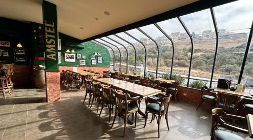 un restaurant avec des tables et des chaises et de grandes fenêtres dans l'établissement Petra Palace Hotel, à Wadi Musa