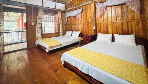 two beds in a room with wooden walls at Pac Ngoi Village's homestay - Hoàng Nguyên in Bak Kan